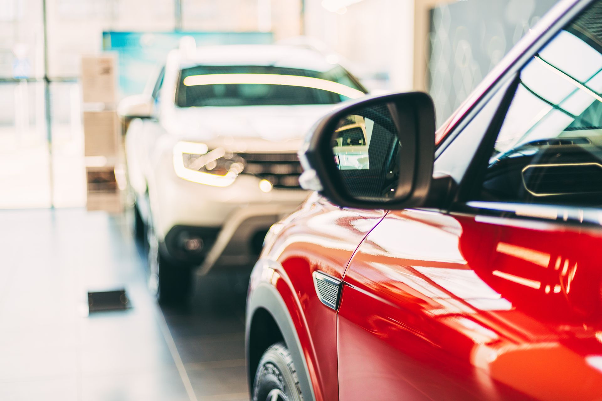 ote und weiße Autos, die im Händlershop geparkt sind. Nahaufnahme des Fahrzeugspiegels. Ausstellungsraum für Händler. Verkauf ote und weiße Autos, die im Händlershop geparkt sind. Nahaufnahme des Fahrzeugspiegels. Ausstellungsraum für Händler. Verkauf