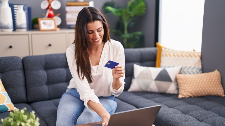 Junge Frau verwendet ihre Kreditkarte am Laptop