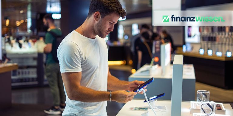 Junger Mann testet ein neues Smartphone im Fachgeschäft.