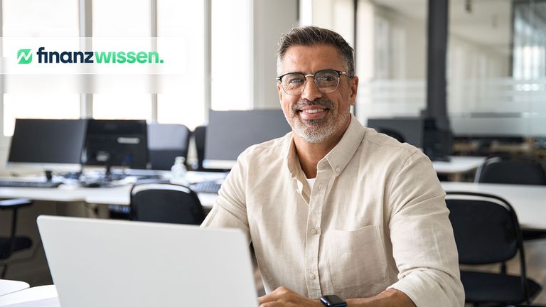 Optionstrader arbeitet am Laptop und blickt lächelnd in die Kamera