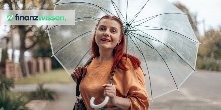 Stilvolle junge Frau in heller Kleidung unter einem transparenten Regenschirm bei schlechtem Wetter im Stadtpark