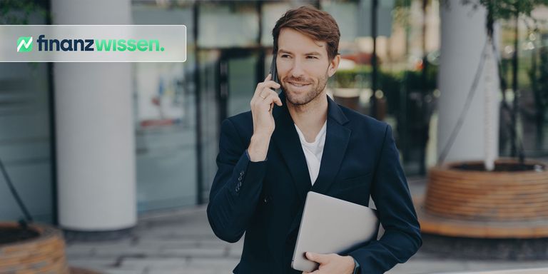 Junger Manager mit Laptop in der einen Hand und Smartphone in der anderen Hand